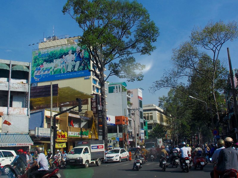 5 kinh nghiệm thuê trọ gần trường Đại học Kinh tế TP.HCM Đường Nguyễn Tri Phương đông xe máy, hai bên là nhà phố và biển quảng cáo
